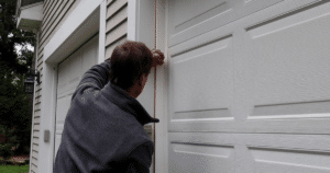 Man seals trim beside white garage door.