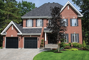 Black Garage Doors on Red Brick House with Elegant Landscaping